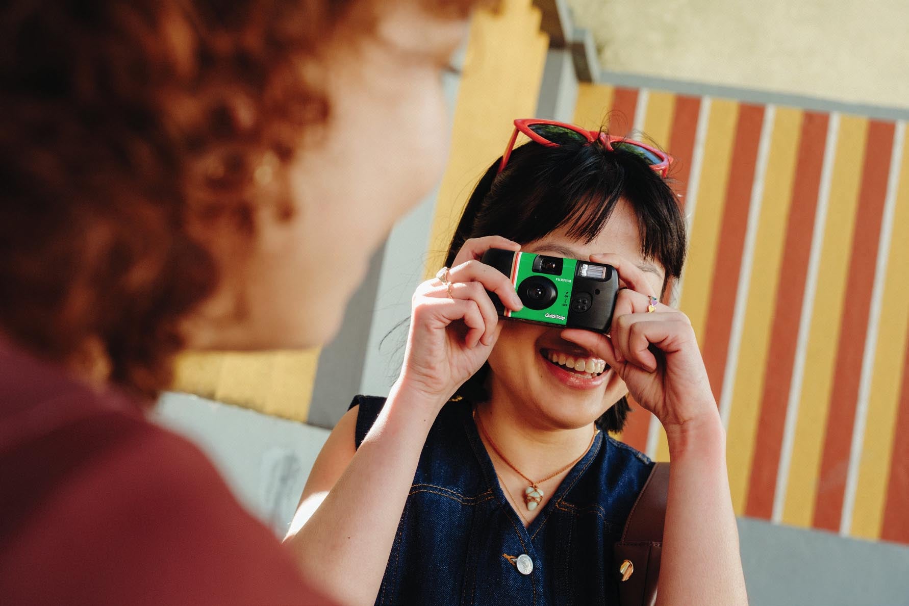 A person taking a photograph with a FUJIFILM QuickSnap camera